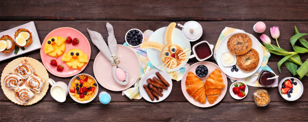 istock Fun Easter breakfast or brunch table scene. Above view on a dark wood banner background. 1370168641