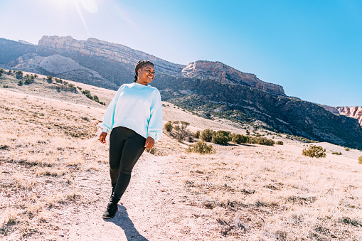 Cute Portrait of a Cheerful Young African American Woman Standing on a Footpath Outdoors While Getting Some Exercise in a Desert Recreational Area Near the Colorado National Monument. She Has Beads in Her Braided Hair