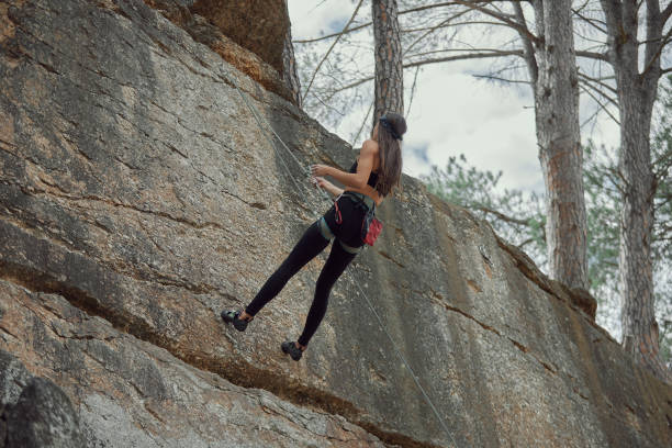 istock Low angle shot of a young rock climbing walking perpendicular to the mountain while scaling a cliff 1370171019