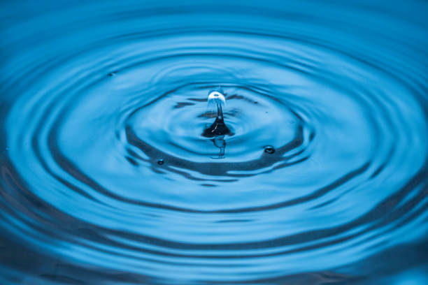 istock Beautiful view of drops making circles on blue water surface isolated on background. 1370171195