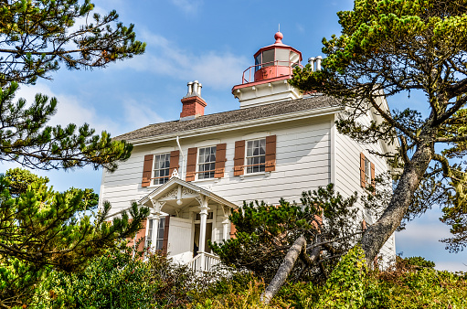 Das Old Yaquina Bay Lighthouse zwischen Bäumen an einem sonnigen Tag in Newport (Oregon)