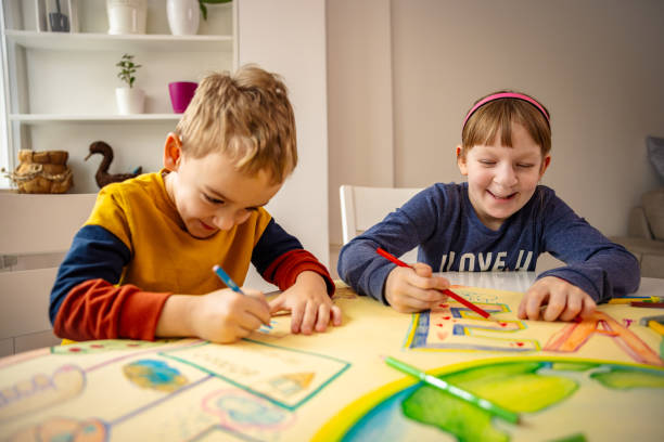 Smiling Caucasian kids making art about sustainability Dedicated Caucasian brother and sister, drawing and coloring the paper with planet Earth in order to raise sustainable lifestyle cleft lip stock pictures, royalty-free photos & images