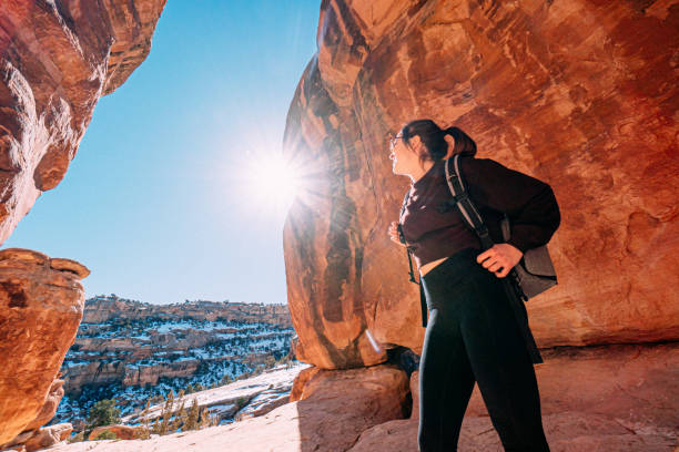 Wide Angle Portrait of a Cheerful Young Woman Standing, Holding Her Backpack Straps, and Enjoying the Views Outdoors While Visiting and Hiking at devil's Kitchen Trail Inside the Colorado National Monument stock photo