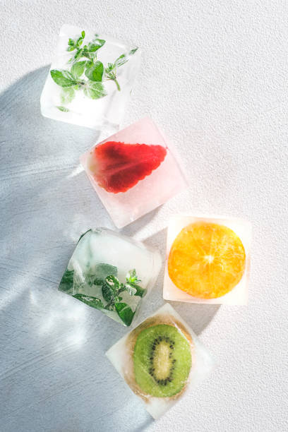 istock Frozen ice cubes with fruits, berries, herbs on a white background. Freezing is a safe method. Home food concept. Bright light, trending shadows. Top view 1370176459