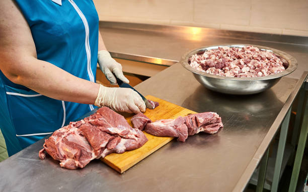 istock Cook cutting raw pork meat on wooden board in kitchen 1370177272