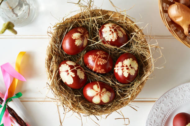istock Easter eggs dyed with onion peels with a pattern of fresh plants on white background 1370180288