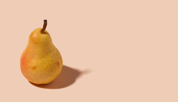 istock Yellow pear on pastel orange background with copy space 1370181075