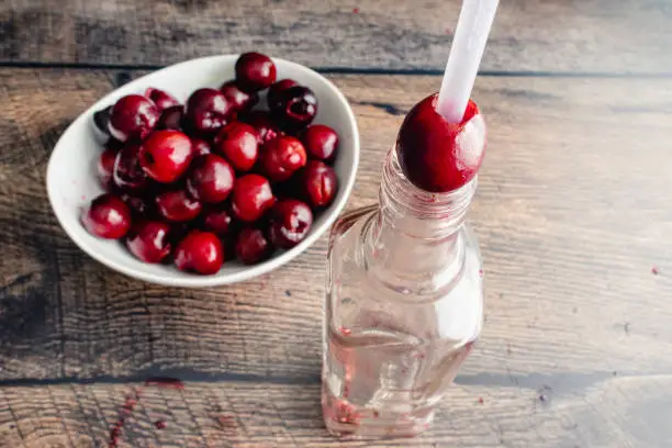 Pitting fresh cherries with a plastic straw and a glass bottle