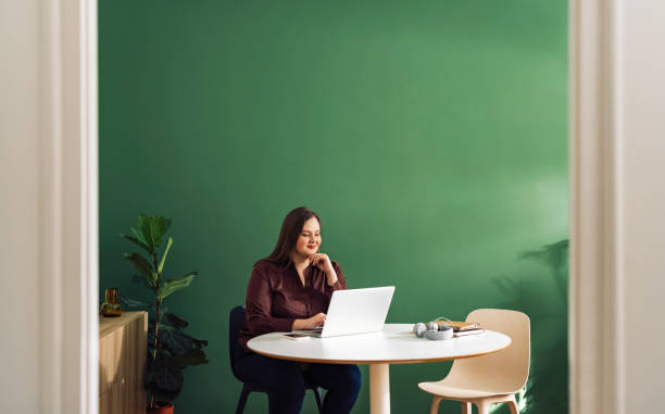 Beautiful Plus Size Businesswoman Working at Home on her Laptop Computer stock photo