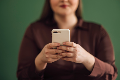 Close up photo of unrecognizable woman hands typing text message on her smartphone.