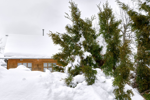 Scenic winter landscape on the top of the mountain, white snow, a rooftop of wooden hut, alps