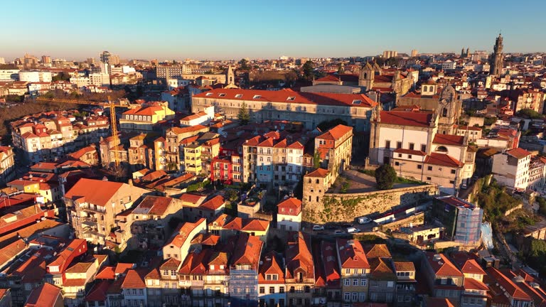 Drone flight over the streets of Porto. Sunrise lights the city blocks of Porto, Portugal. Cityscape of white houses with red roofs.
