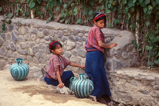 San Antonio Palopo, Atitlan, Guatemala - aug 17, 1998: two girls draw water from a public fountain using colored plastic jars, not very traditional.