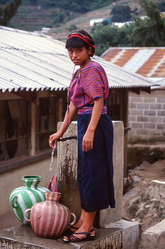 San Antonio Palopo, Atitlan, Guatemala - aug 17, 1998: in San Antonio Palopo, a young woman fills two plastic jars with water for household needs.