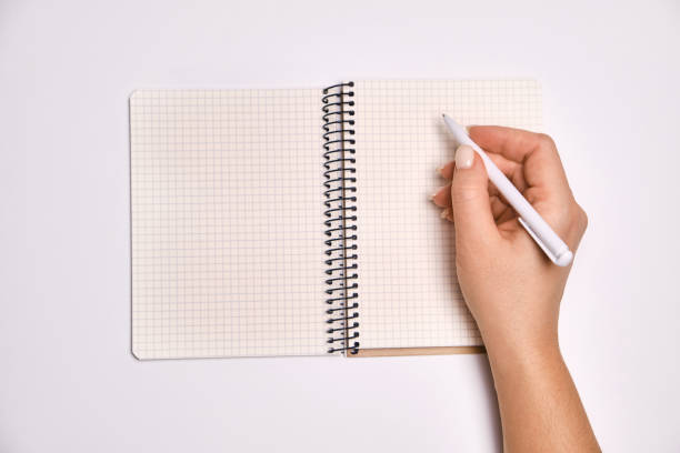 istock Woman's hand holding pen and open spiral notebook with blank white pages 1370195380