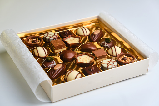 A set of assorted chocolates in a paper box on a bright background for Valentine's Day, mother's day, women's day on white background. sweets, confectionery and food concept