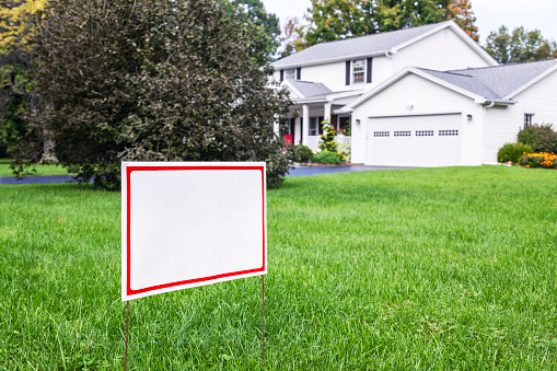 A blank white yard sign on a suburban home front lawn on a drizzly, rainy, late summer day. Lawn sign, yard sign, home improvement/maintenance contractor placard or sign, lawn care or other service business sign or placard, For Sale sign, Garage Sale or Yard Sale sign, etc.