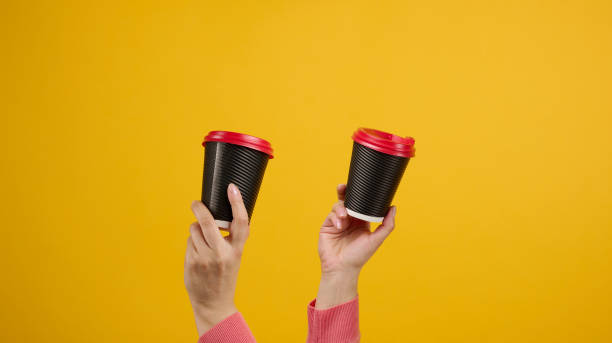 istock hand holds paper cardboard brown cup for coffee, yellow background. Eco-friendly tableware 1370201987