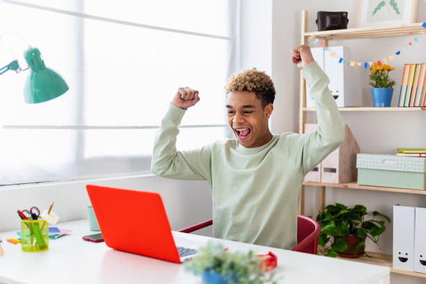 Excited teenage high school student celebrating exam result in online campus stock photo