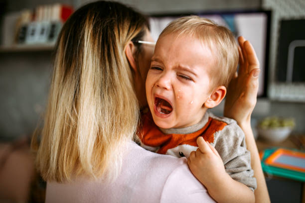 istock Baby boy is crying while mother holding him in arms 1370211005