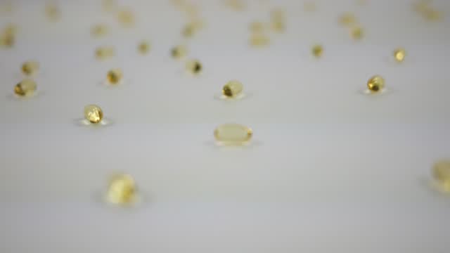 Clear Gold Vitamin D Capsules Spinning Over White Background