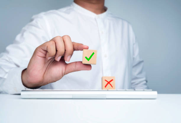 Green check mark icon, on wooden cube block in businessman's hand and red cross symbol on keyboard computer. True or false changing mindset, correct, making choice, yes or no concept. Green check mark icon, on wooden cube block in businessman's hand and red cross symbol on keyboard computer. True or false changing mindset, correct, making choice, yes or no concept. checkbox yes asking right stock pictures, royalty-free photos & images