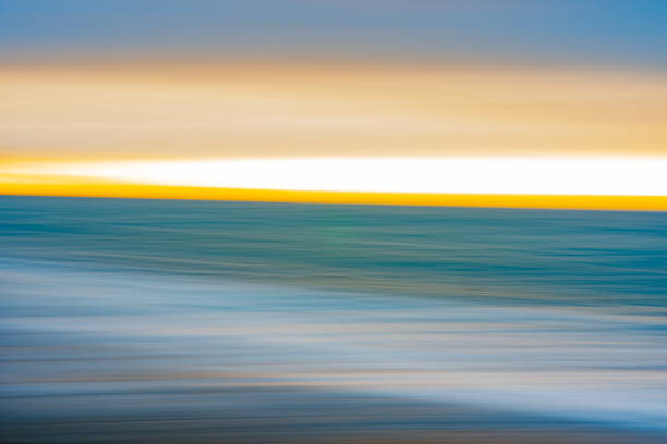 Impressionist abstract effect of beach and sea in long exposure and using intentional camera movement background or artistic image.in blue and gold.