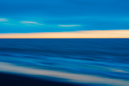 Impressionist abstract effect of beach and sea in long exposure and using intentional camera movement background or artistic image in blue.