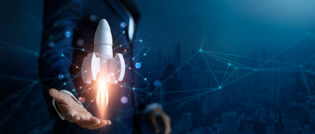 Startup business concept, Businessman control white rocket is launching and soar flying out from hand to sky for growth business,  Fast business success. Network connection on city background.