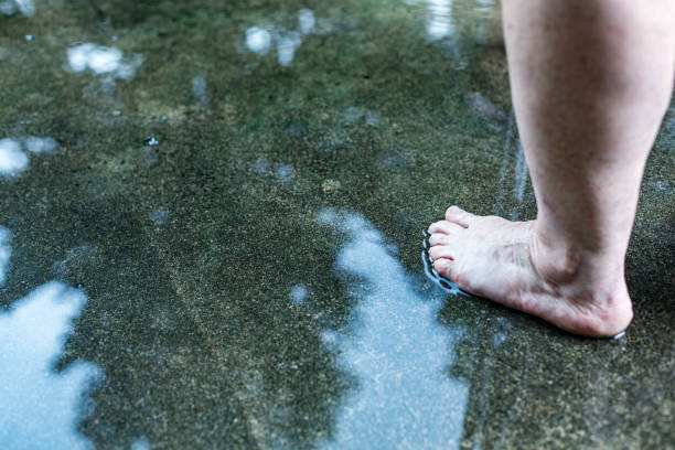 istock Barefoot Woman Standing in Water Puddle on Concrete Floor 1370236079