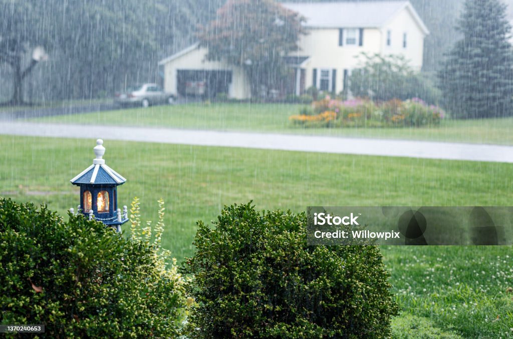 Illuminated Model Lighthouse During Drenching Rain Storm Downpour A front yard wooden replica model lighthouse is illuminated during a drenching downpour late August extreme weather summer rain storm near Rochester, in western New York State. Rain Stock Photo