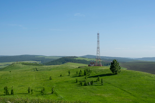 Telecommunications tower with a digital television antenna on top of a hill. Rural landscape.