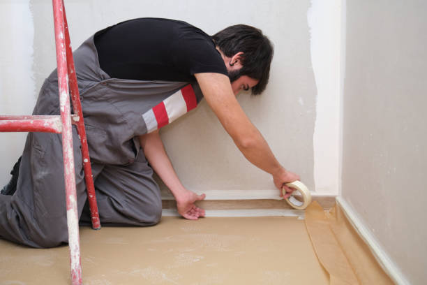 painter using tape to cover the skirting board before painting the room. - paint preparation adhesive tape indoors imagens e fotografias de stock