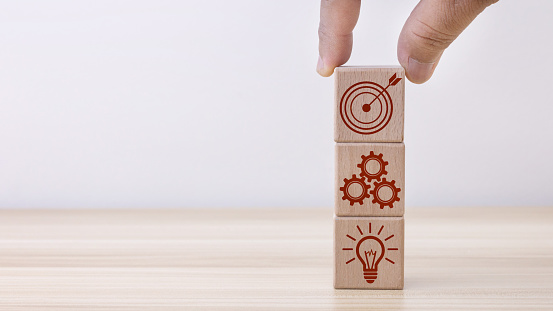 Concept of business strategy and action plan. Businessman hand putting wood cube block on top with icon