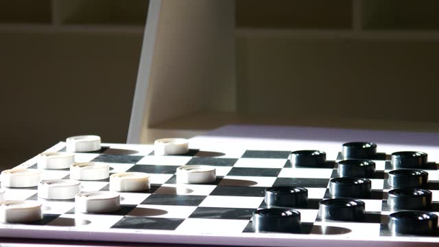 Close-up of a checkers board and a man’s hand cuts down a black checker