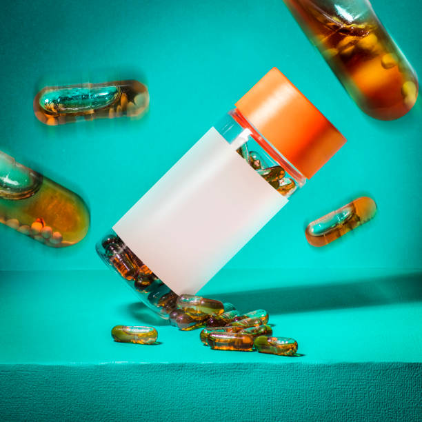 Medicine supplement pill bottle blank label with pills on blue teal background Medicine supplement pill bottle blank label with pills falling in air on blue teal background vitamin photos stock pictures, royalty-free photos & images