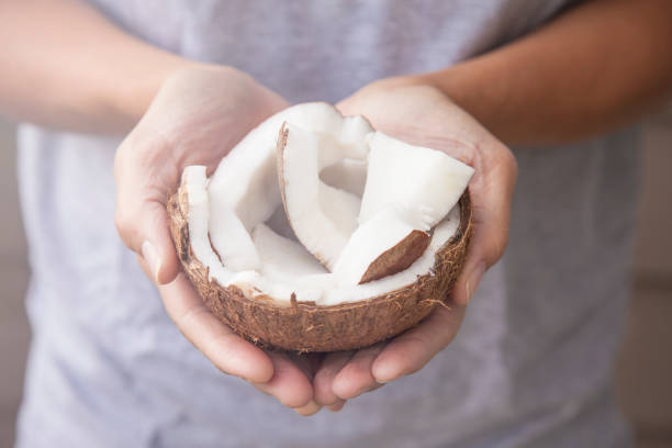 istock Woman's hands holding cracked open fresh raw coconut 1370263606