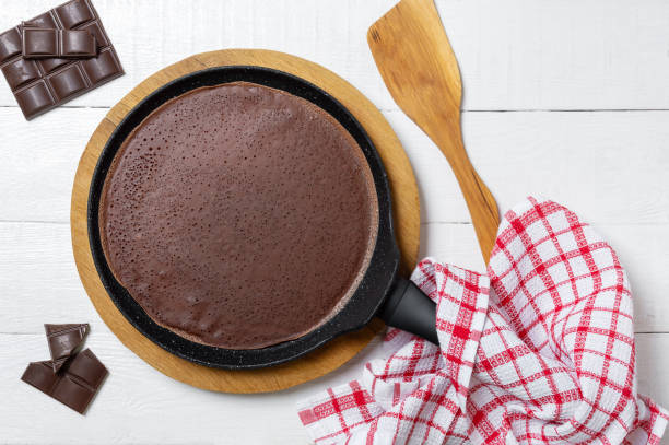 istock Chocolate thin pancake in a pan on a wooden stand. Tasty breakfast. 1370264136