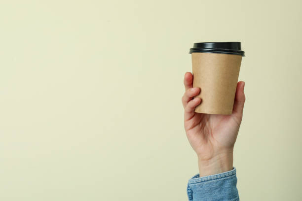 istock Female hand hold paper cup on beige background 1370265003