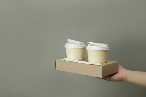 istock Female hand hold paper cups on gray background 1370265877