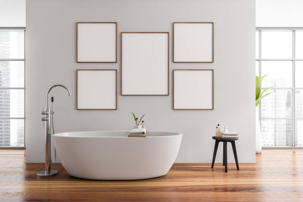 istock Modern bathroom interior with ceramic bathtub and five framed posters above tub. Hardwood flooring. Panoramic window. No people. Mockup. 3d rendering. 1370266090