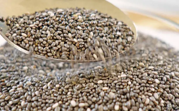 Close up view of a spoon pouring chia seeds with a blur motion effect.
