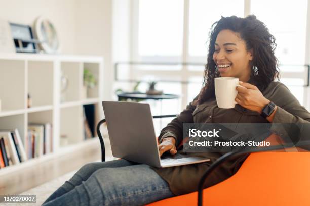 Smiling Black Lady Watching Video On Computer Drinking Hot Coffee Stock Photo - Download Image Now