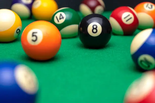 Photo of BILLIARD BALLS ON A POOL TABLE. THE EIGHT BLACK ONE IN FOCUS. LEISURE CONCEPT.