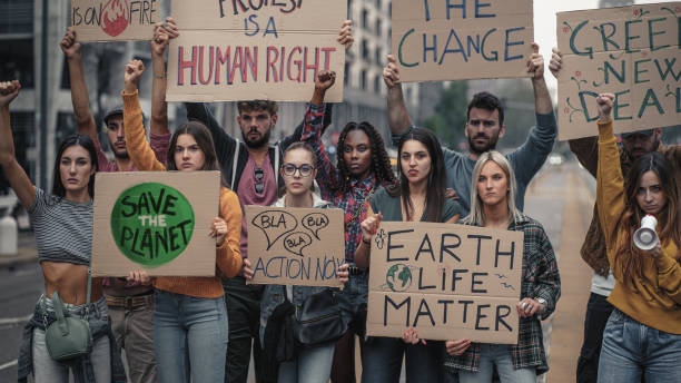 istock Crowd of young people protesting against climate policy and global warming with raised fists and slogans on placards - concept that illustrates the sensitivity of generation z towards social problems 1370272306