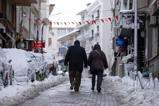 The old man and woman are going home in the snow.
Old man and woman walking in Istanbul on a snowy day in winter.