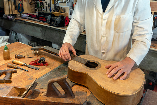 LUTHIER RESTORING A CLASSICAL GUITAR IN THE WORKSHOP. CRAFTSMAN CONCEPT.