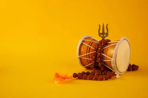 Shivaratri background with Shivas trident and Pellet Drum Damroo musical instrument . Hindu festival Maha Shivratri.