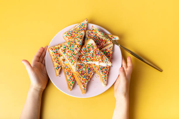 Fairy bread in hand. The famous traditional Australian food Fairy Bread on a yellow background Fairy bread in hand. The famous traditional Australian food Fairy Bread on a yellow background. downunder stock pictures, royalty-free photos & images