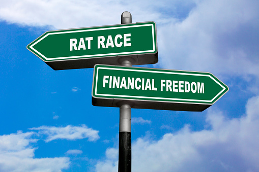 Two direction signs, one pointing left (Rat race), and the other one, pointing right (Financial freedom).